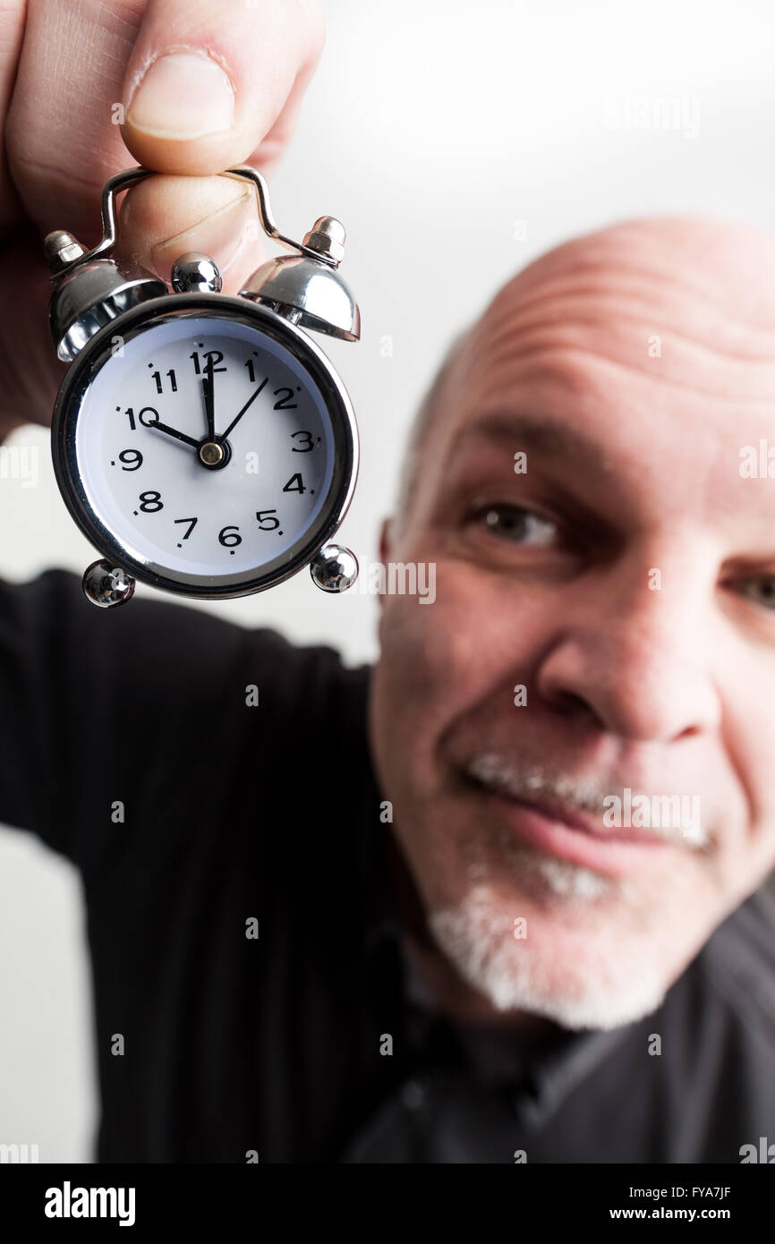 wideangle closeup portrait of a man holding an alarm clock claiming ...