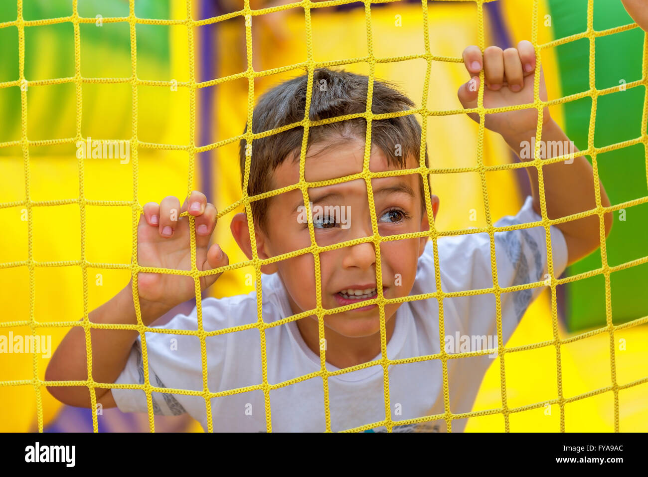 Young child blond boy climbing rope net in playground summer Stock