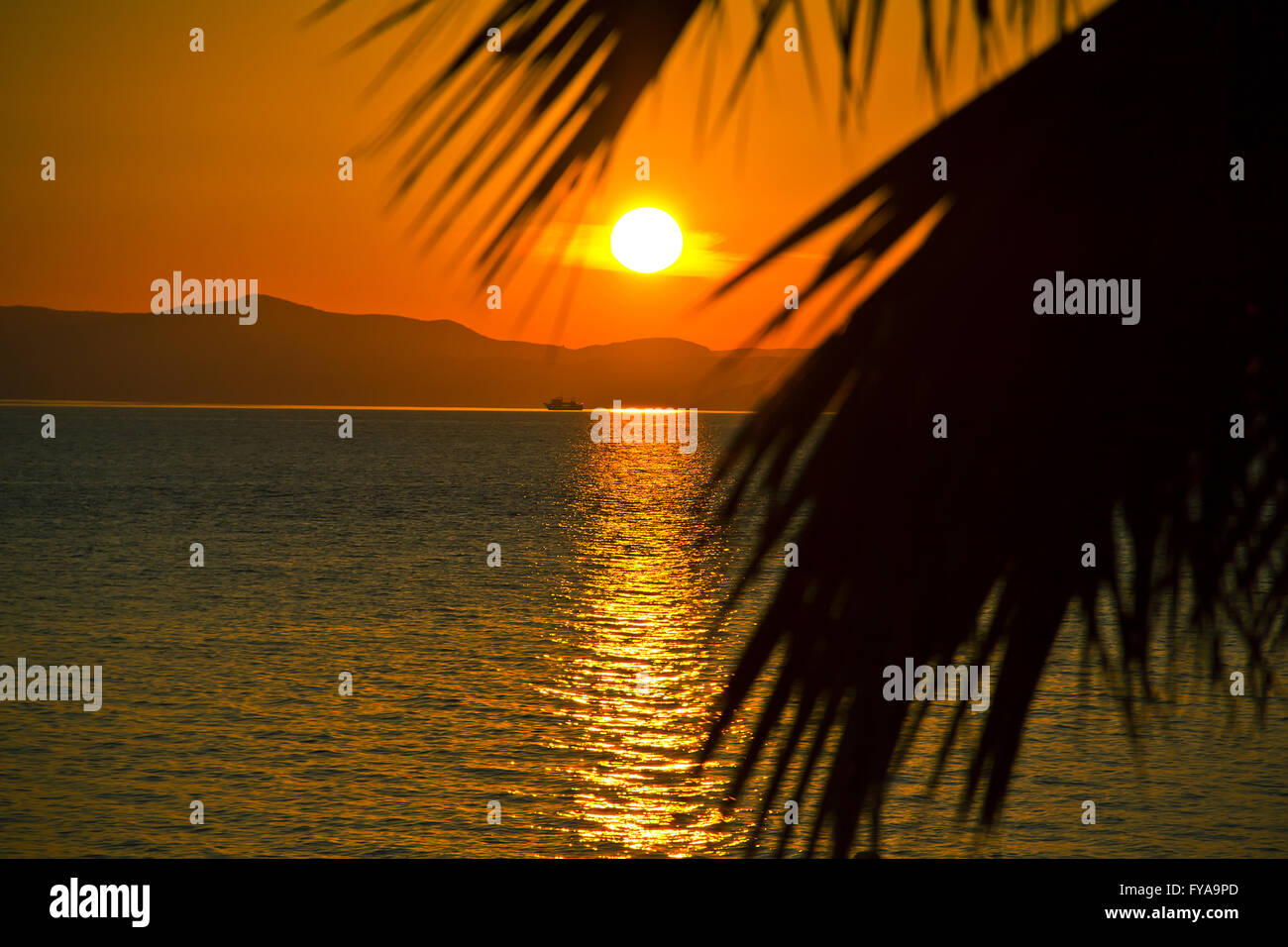 Sunset over the sea and a lone ship Stock Photo - Alamy