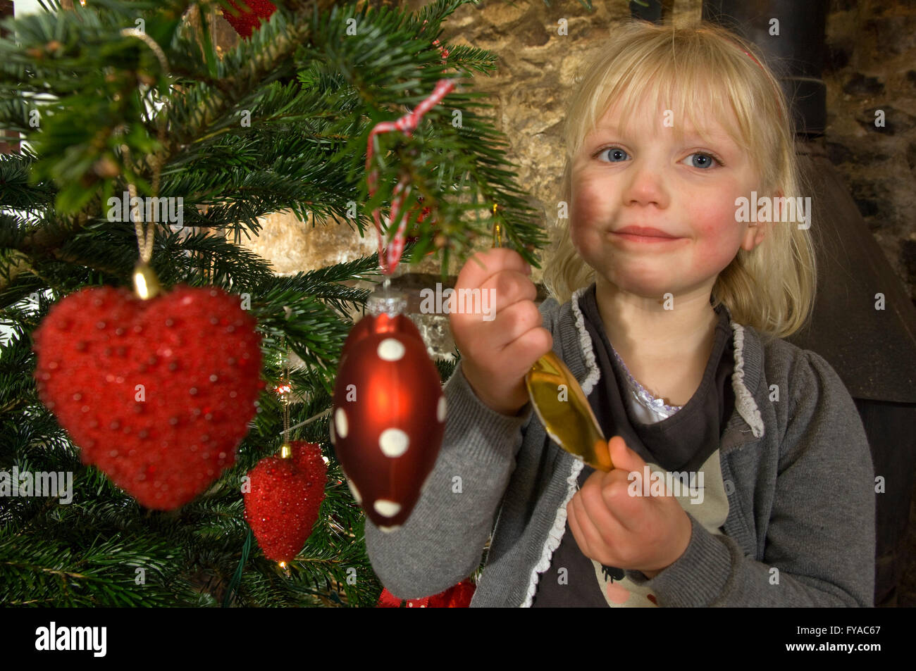 A young girl decorating a traditional Christmas tree with coloured