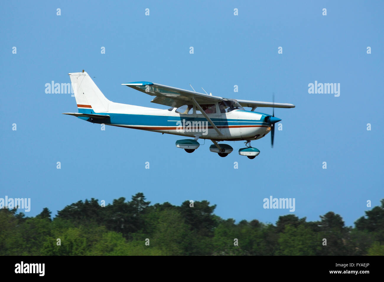 Light general aviation  plane on final over green trees Stock Photo