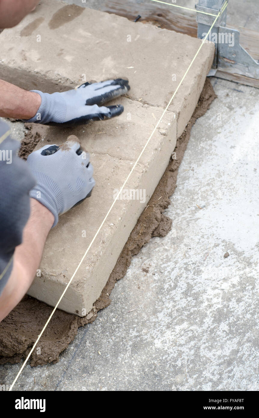 Construction worker lays the first brick of the wall. Mud bricks