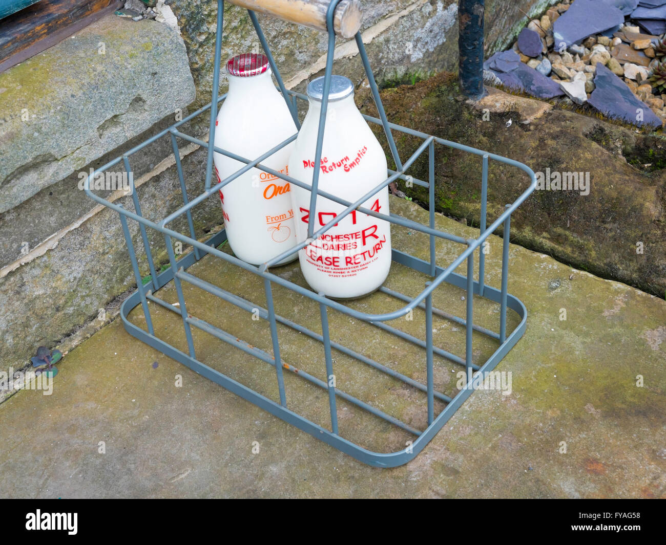 Two bottles of freshly delivered milk in a crate on a doorstep in a Yorkshire village Stock Photo