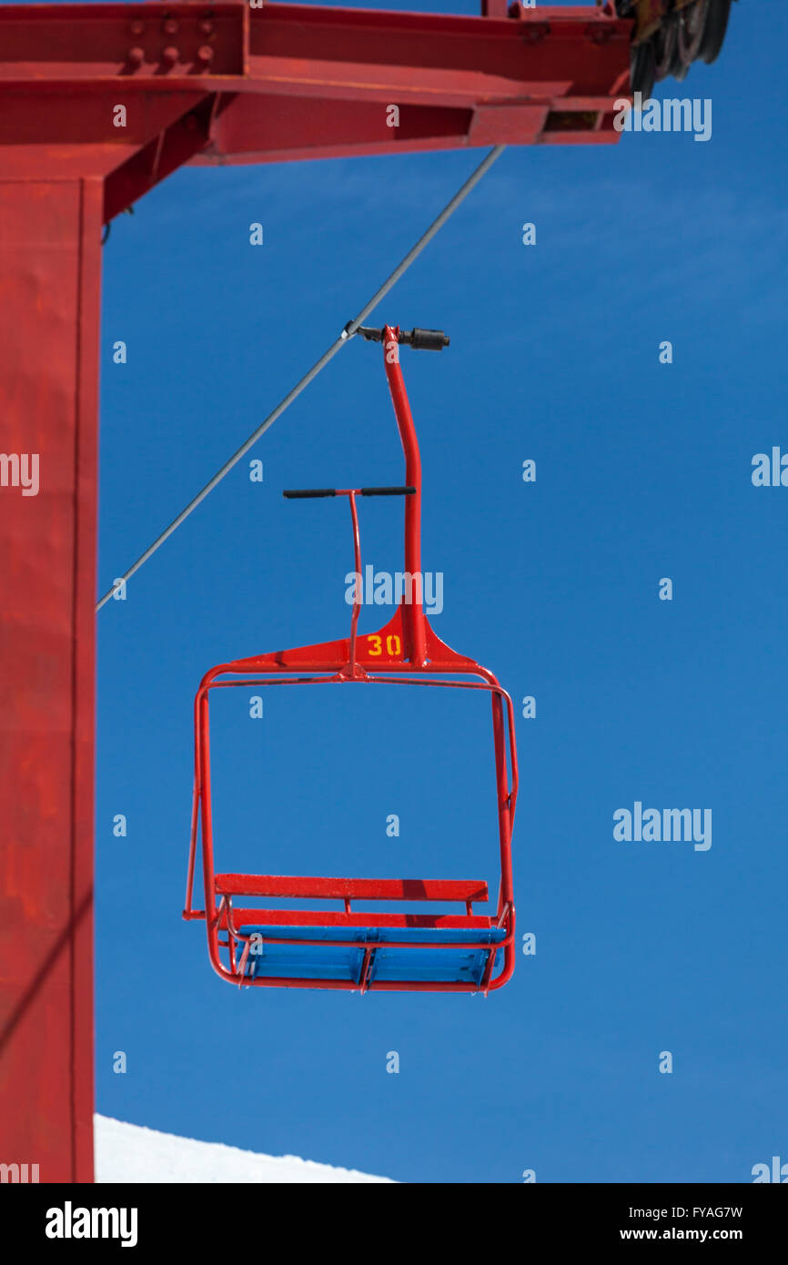 empty chair of ski lift going down from the peak of the mountain Stock Photo