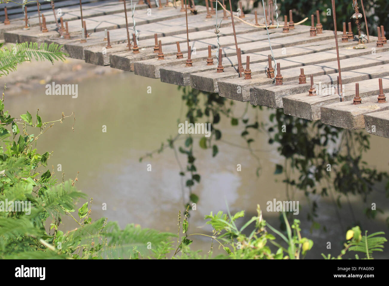 View on a wooden suspension bridge over dirty river in the forest. Serengeti National Park, Tanzania Stock Photo