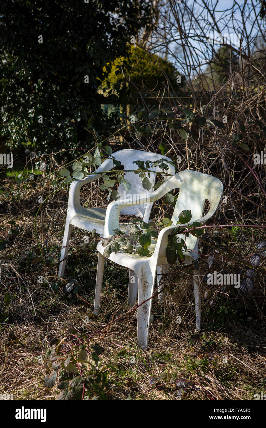Old White Plastic Chairs Lost Amongst An Over Grown Garden Stock Photo Alamy
