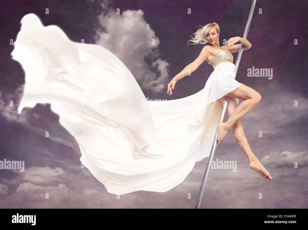 a women in a dress pole dancing in front of sky Stock Photo