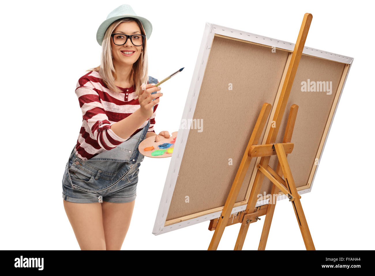Young woman painting on a canvas and looking at the camera isolated on white background Stock Photo