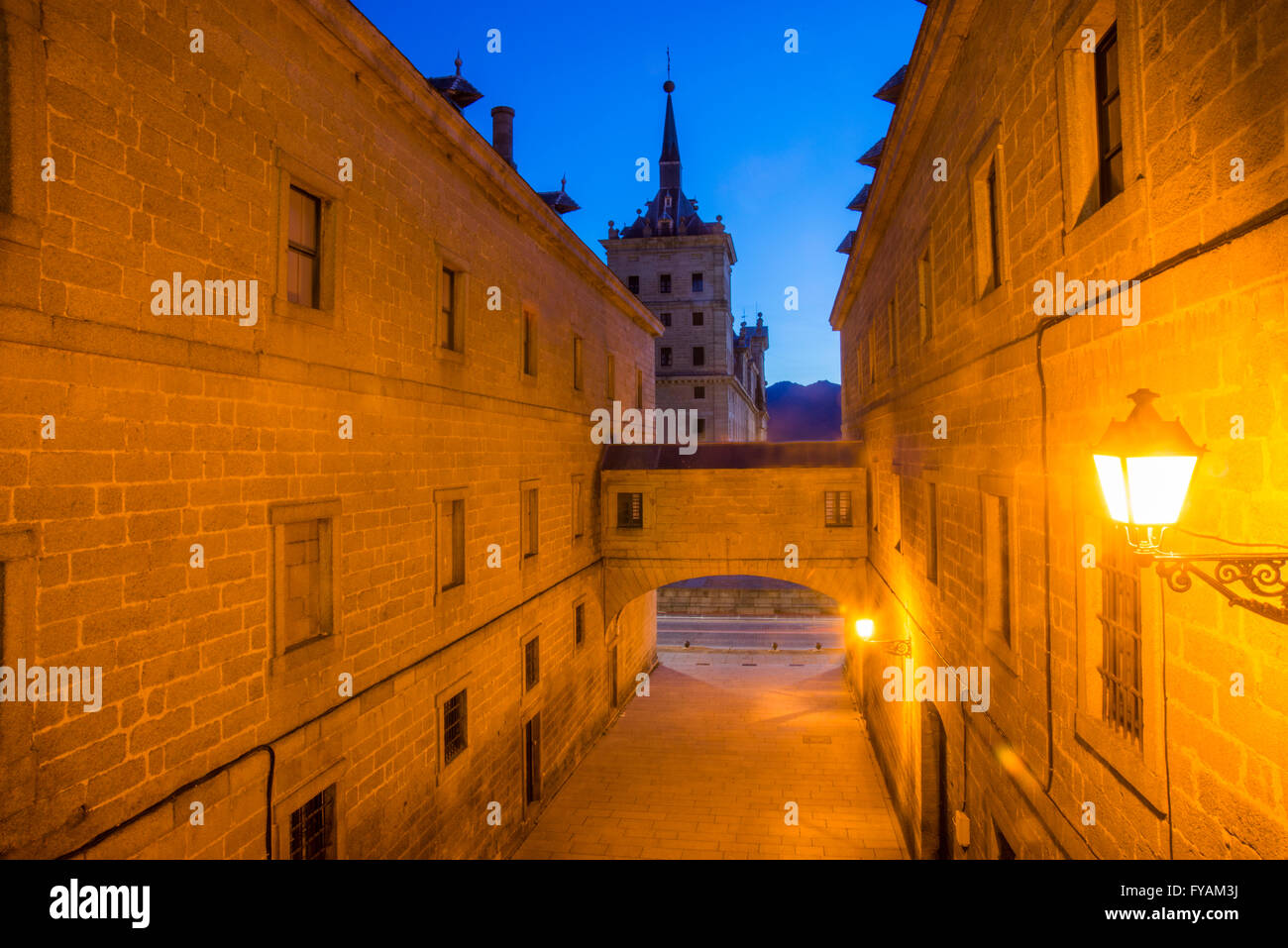 Street, arch and Royal Monastery, night view. San Lorenzo del Escorial, Madrid province, Spain. Stock Photo