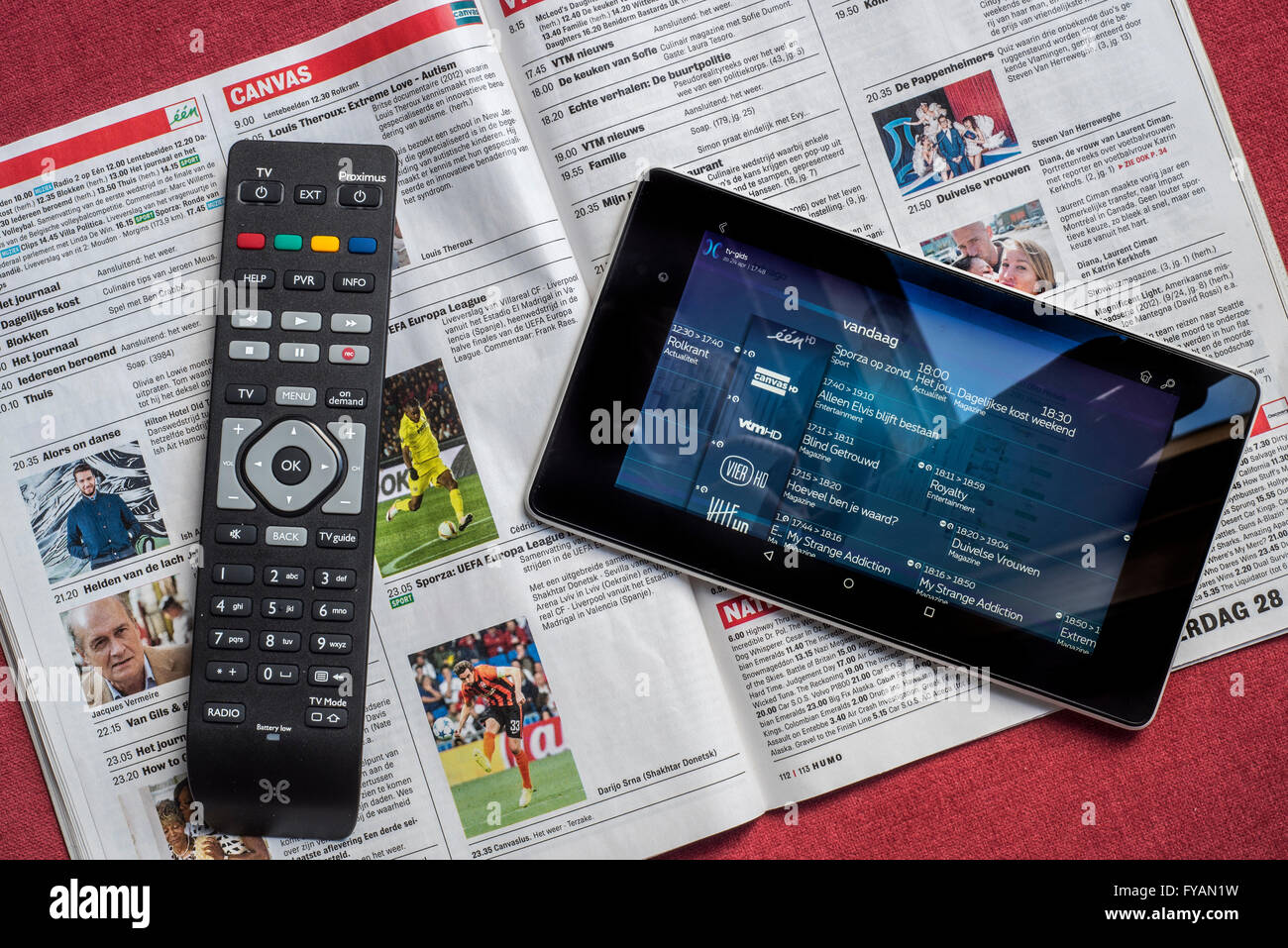 Remote control and tablet showing television channels on top of open