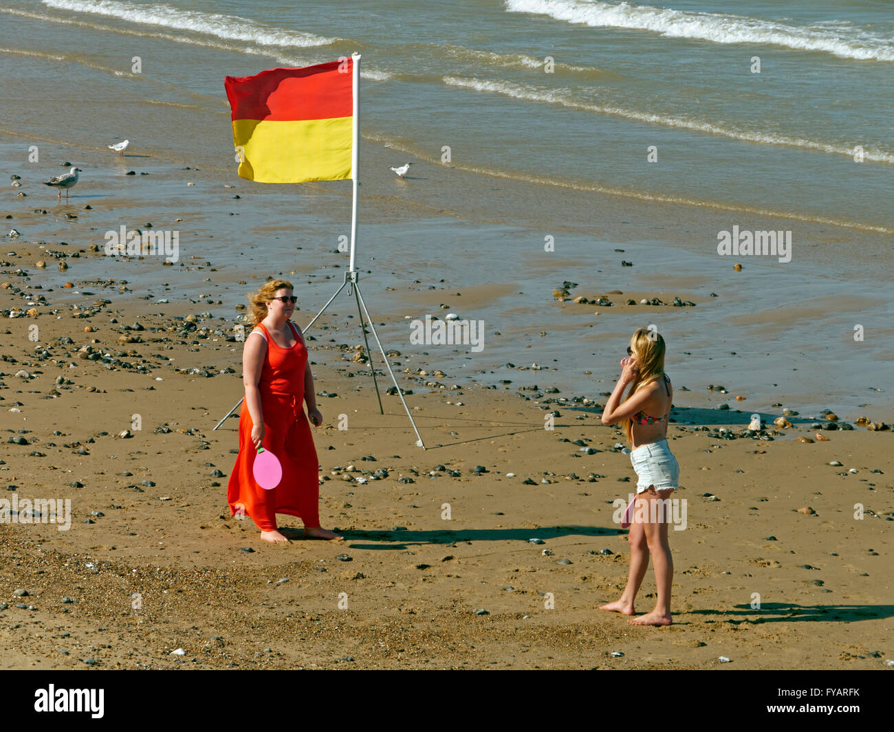 Two Young Ladies playing bat and ball game on beach at Mundesley in Norfolk England Stock Photo