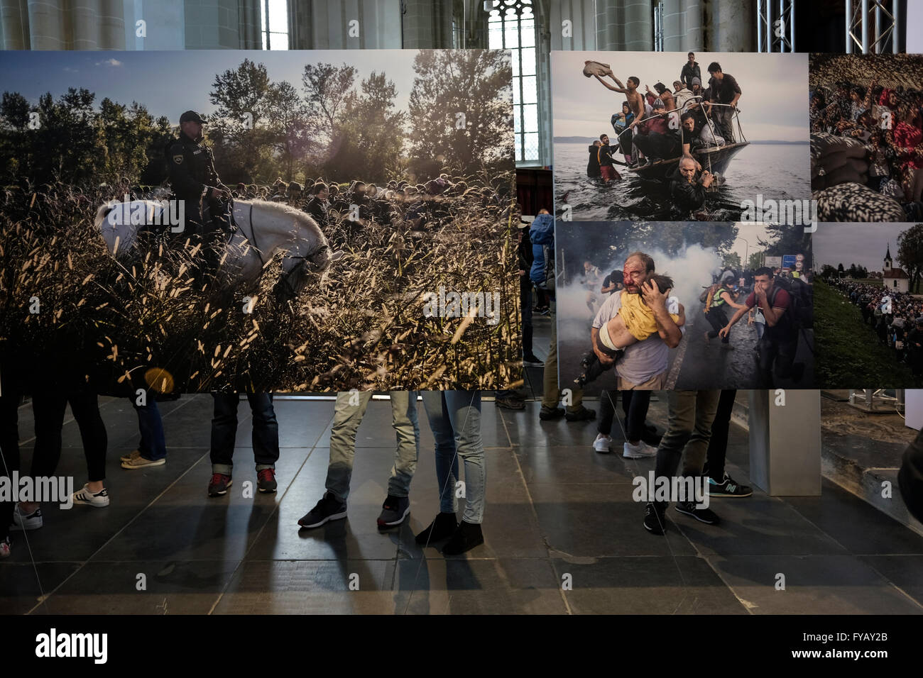 Visitors watching photos depicting refugee fleeing into Europe at the 2016 World Press Photo exhibition inside the Nieuwe Kerk a 15th-century church  located on Dam Square in Amsterdam Netherlands Stock Photo