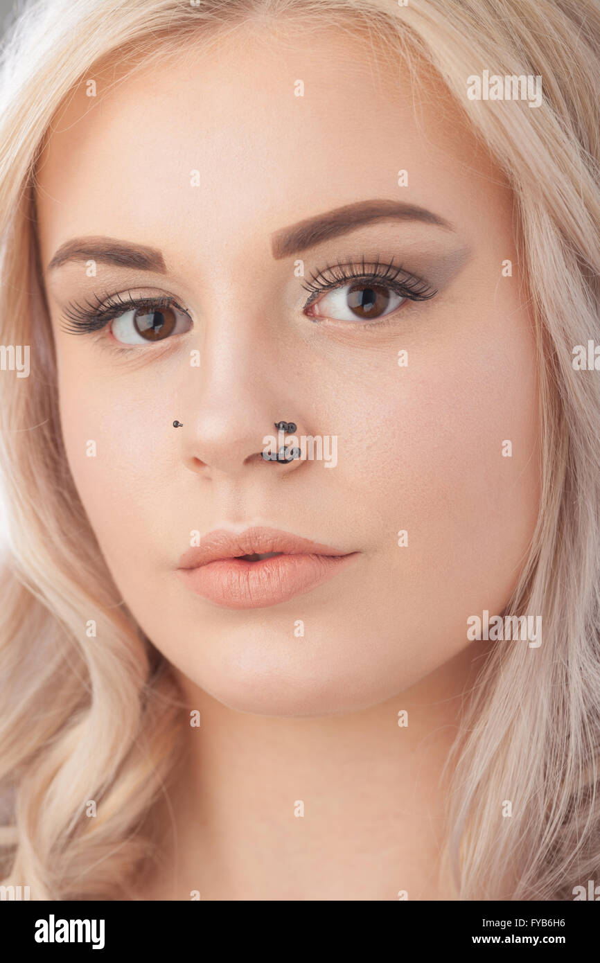 Close up of a blond teenage girls face with nose piercing. Stock Photo