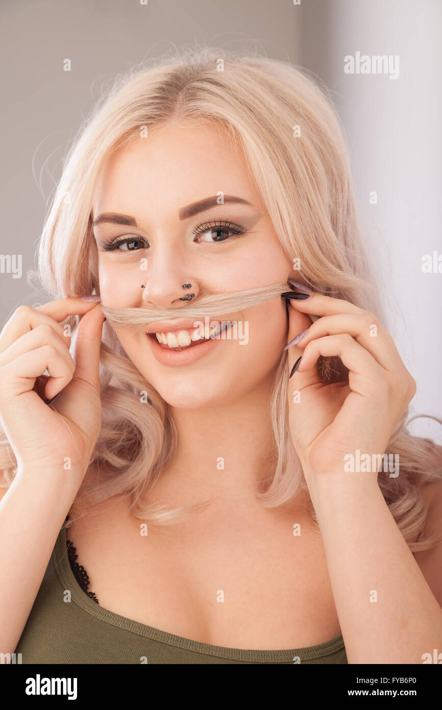 Blond girl using her long hair as a playful Mustache. Stock Photo