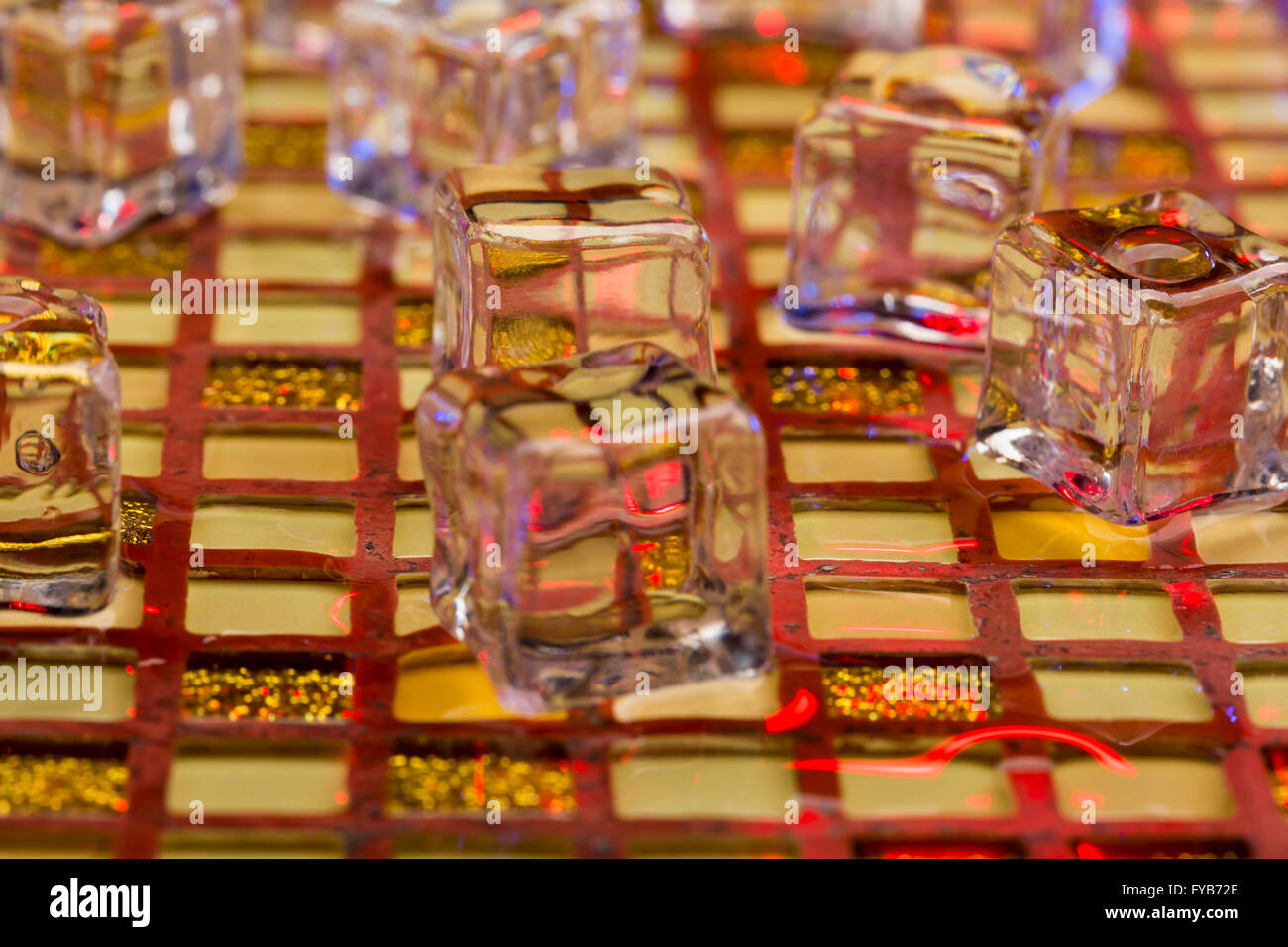 Cold and wet ice cubes on colorful glitter background Stock Photo