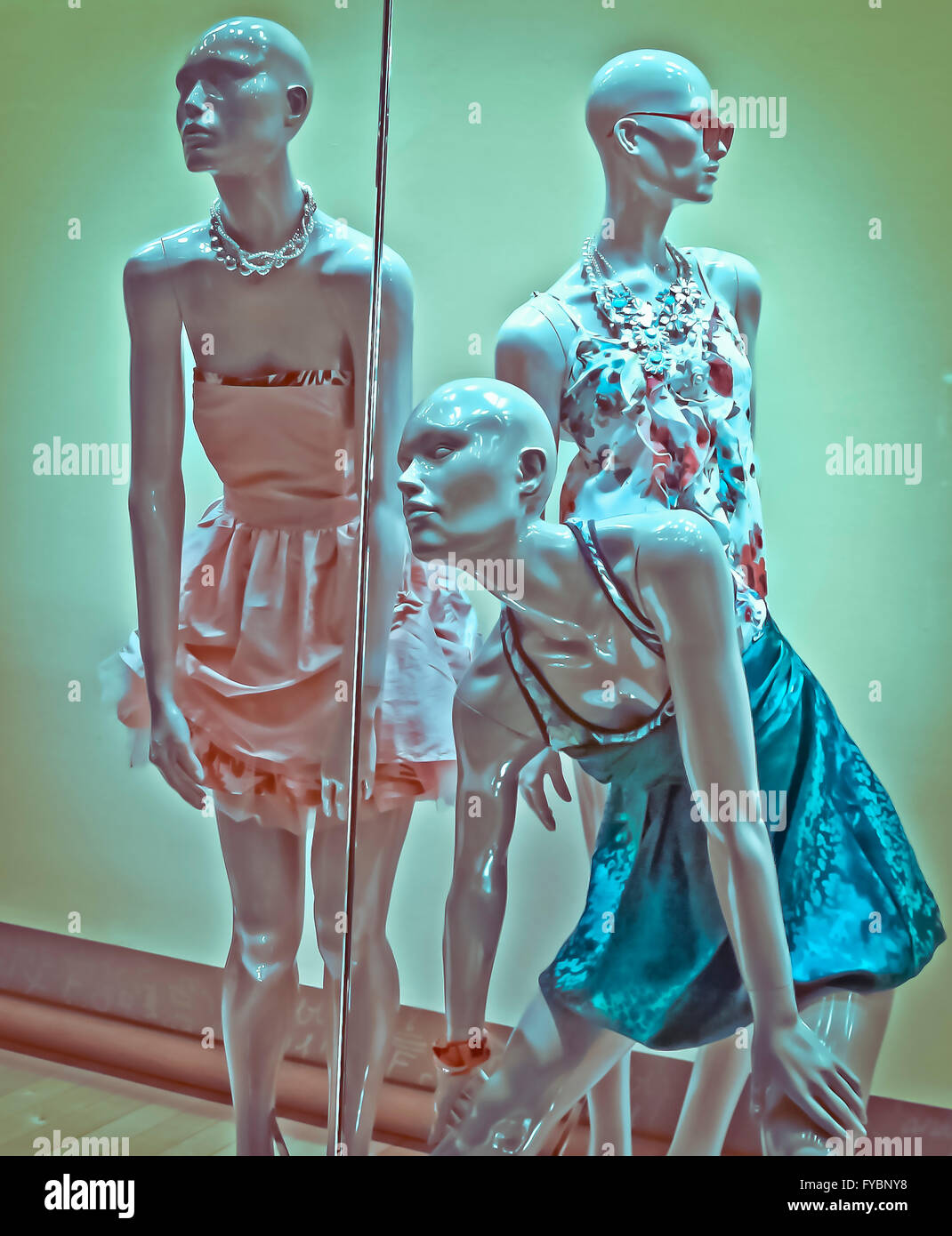 Mannequins  starring out from the window display with summer dress on. Stock Photo