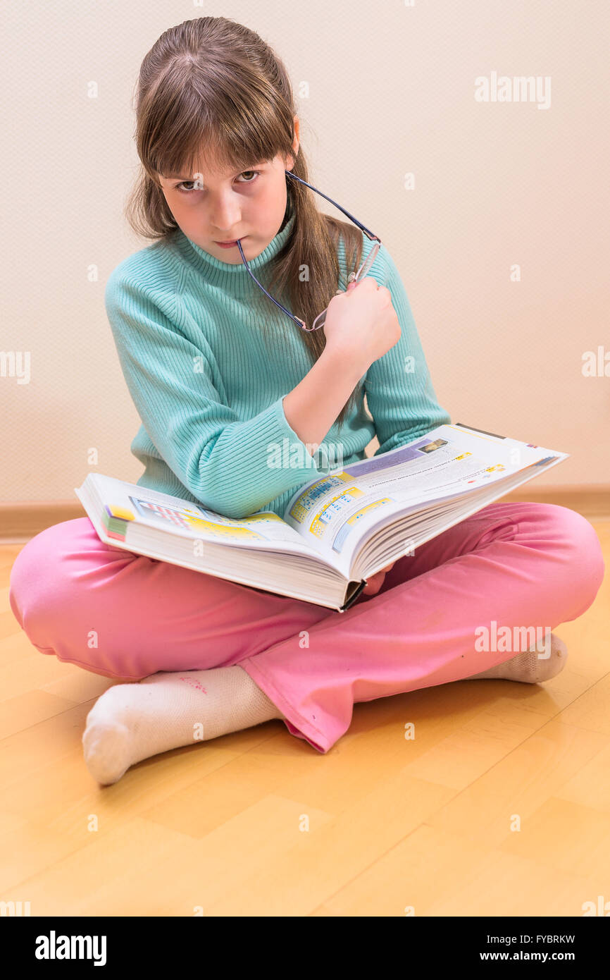 Young little girl sitting on floor reading book Stock Photo - Alamy