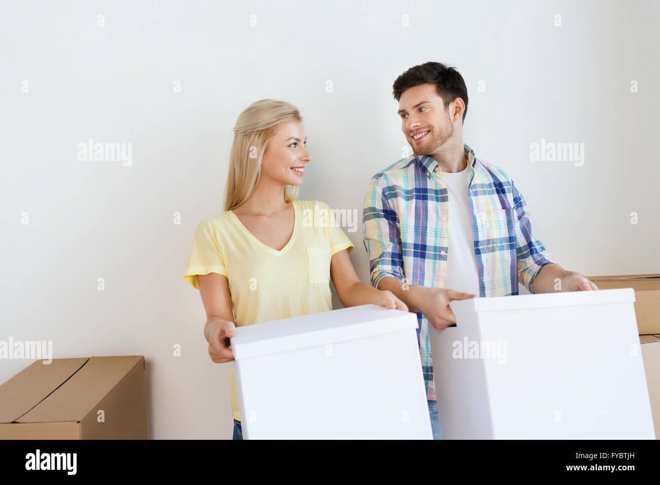 smiling couple with big boxes moving to new home Stock Photo - Alamy