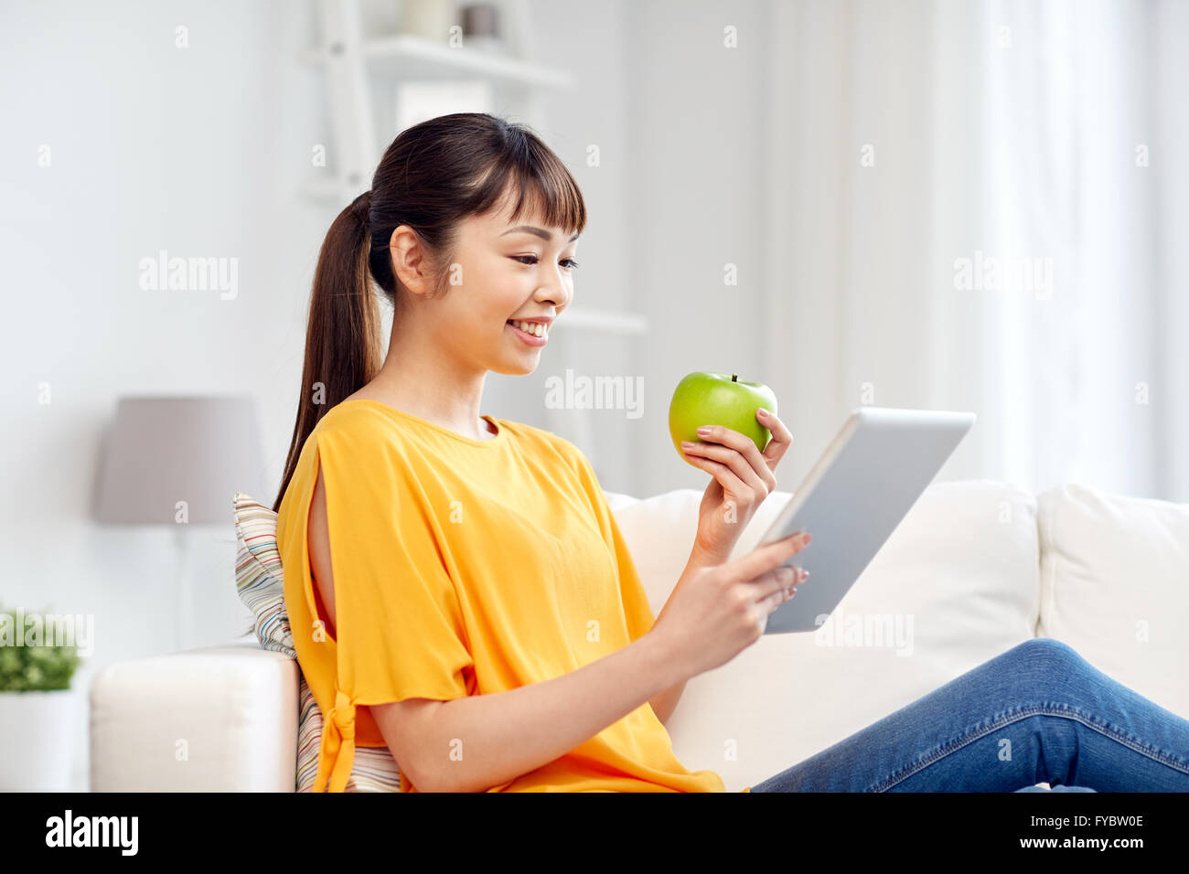 happy asian woman with tablet pc and apple at home Stock Photo - Alamy
