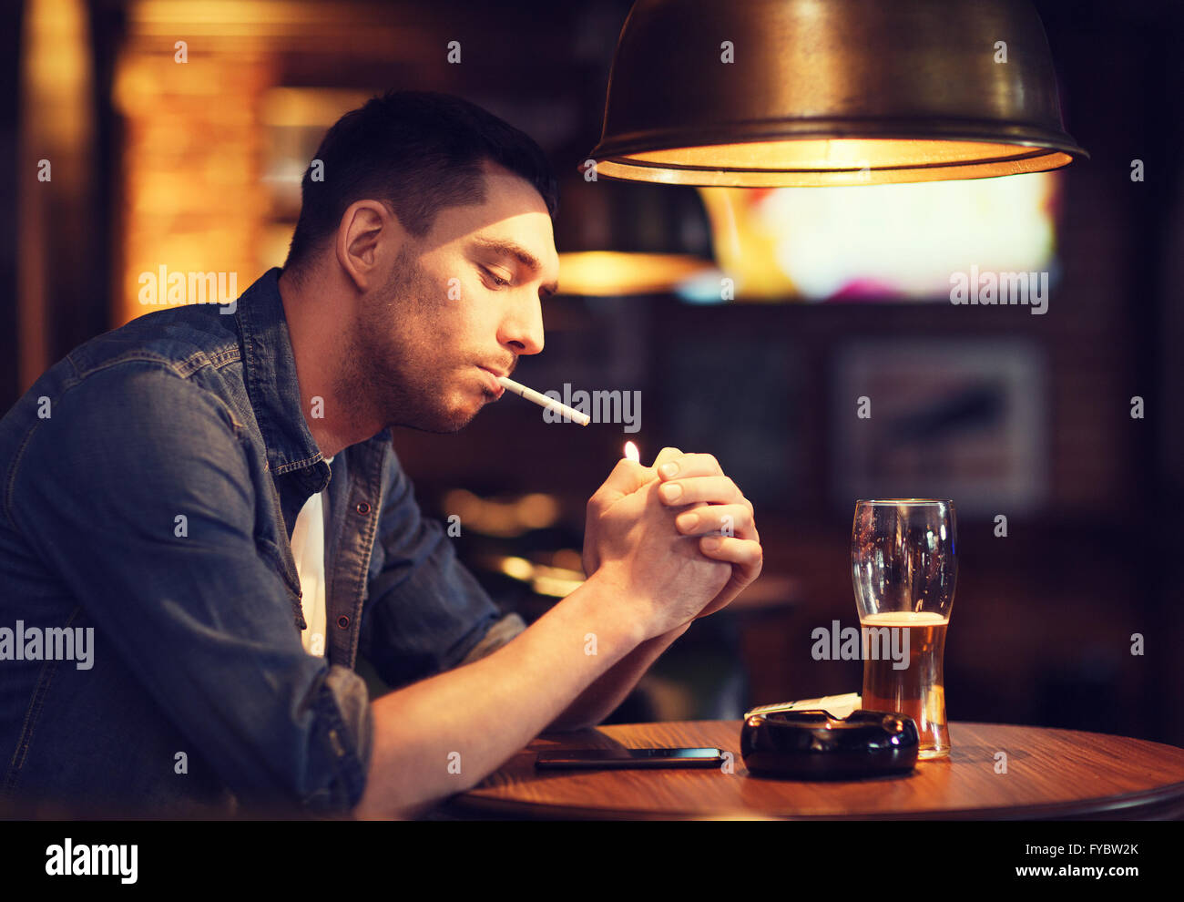 man drinking beer and smoking cigarette at bar Stock Photo Alamy