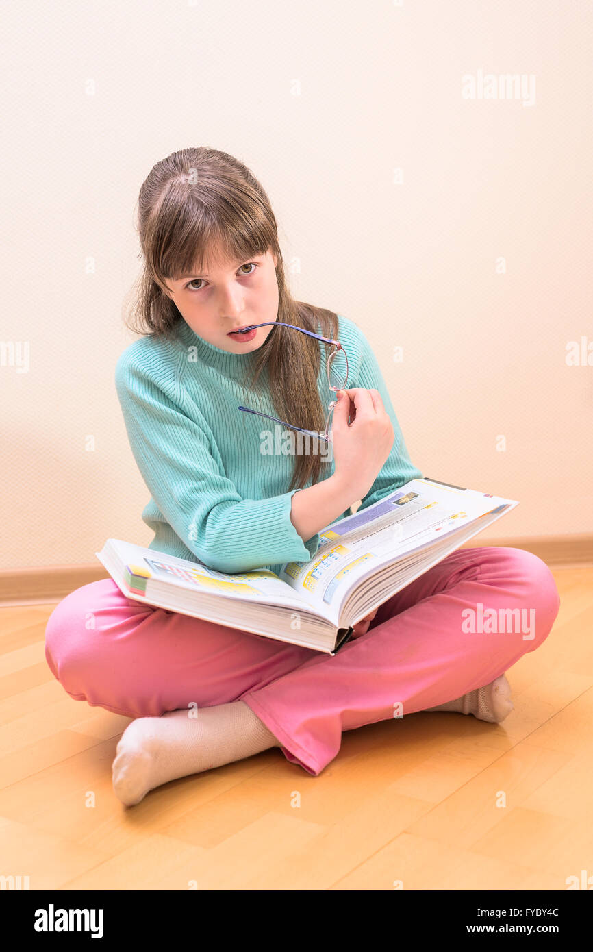 Young little girl sitting on floor reading book Stock Photo - Alamy