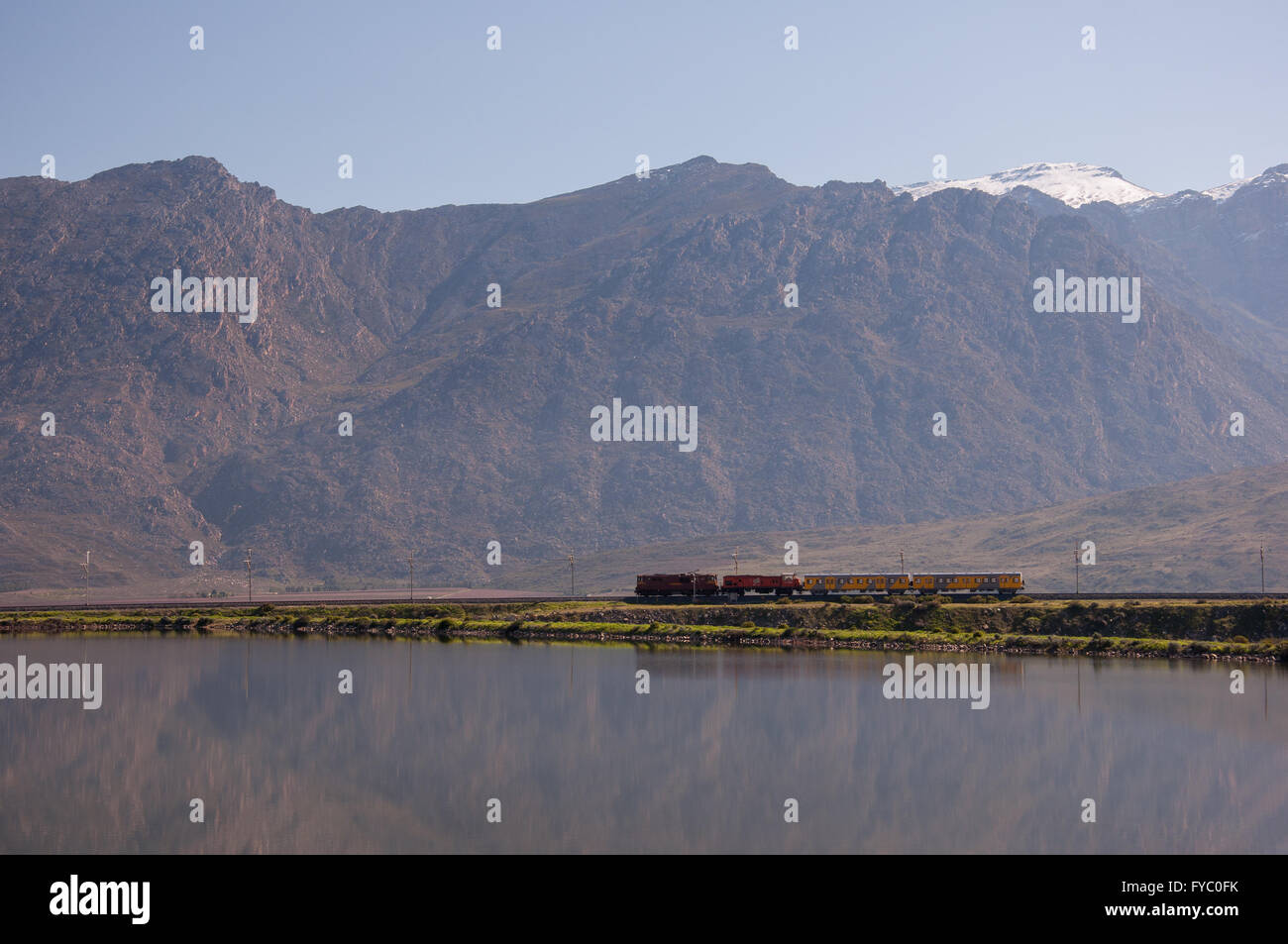 Train traffic southbound in the vicinity of Worcester town, with the mighty Hex River Mountains looming in the background. Stock Photo