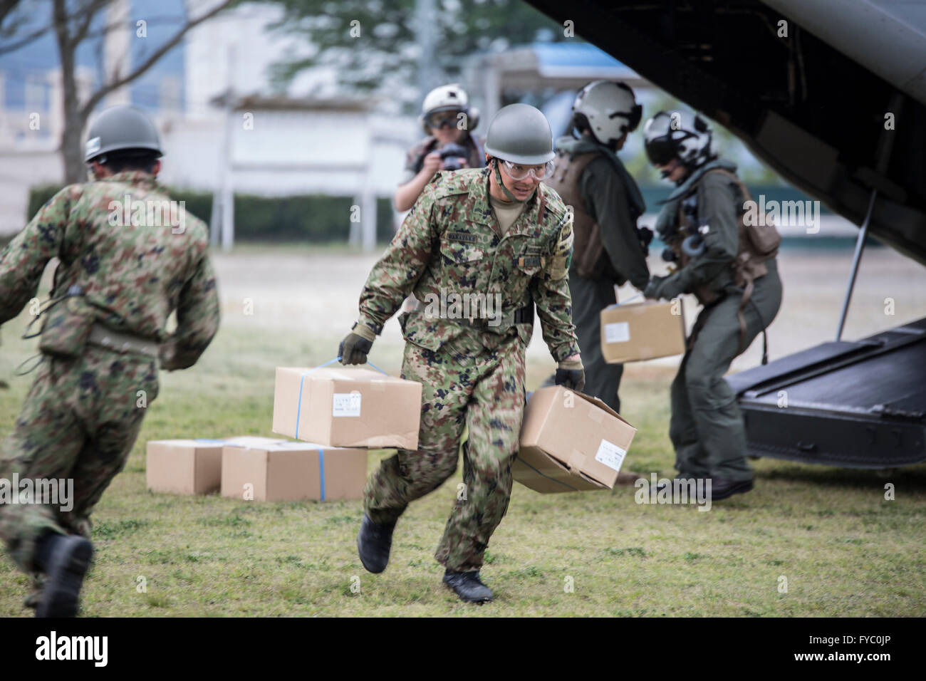 Japanese Self-Defense land force soldiers unloading humanitarian aid for those affected by recent earthquakes from a U.S. Marine Corps Osprey aircraft in Kumamoto April 18, 2016 Takayubaru, Japan. The U.S joined thousands of Japanese troops to help victims of two massive earthquakes that struck the Kyushu region. Stock Photo