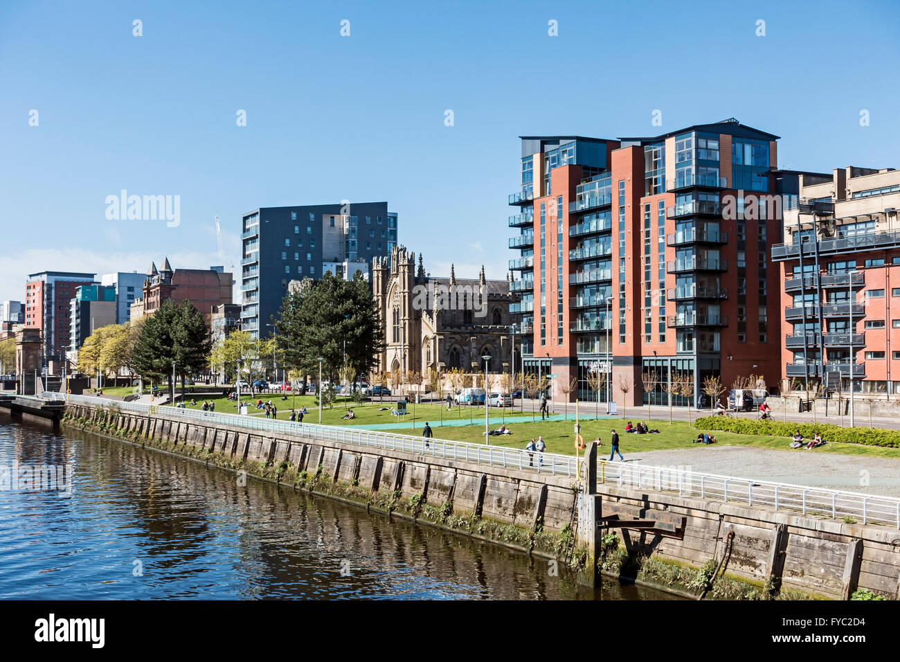 Line-up of buildings along Clyde Street at River Clyde in Glasgow Scotland with people enjoying the sun shine at midday Stock Photo