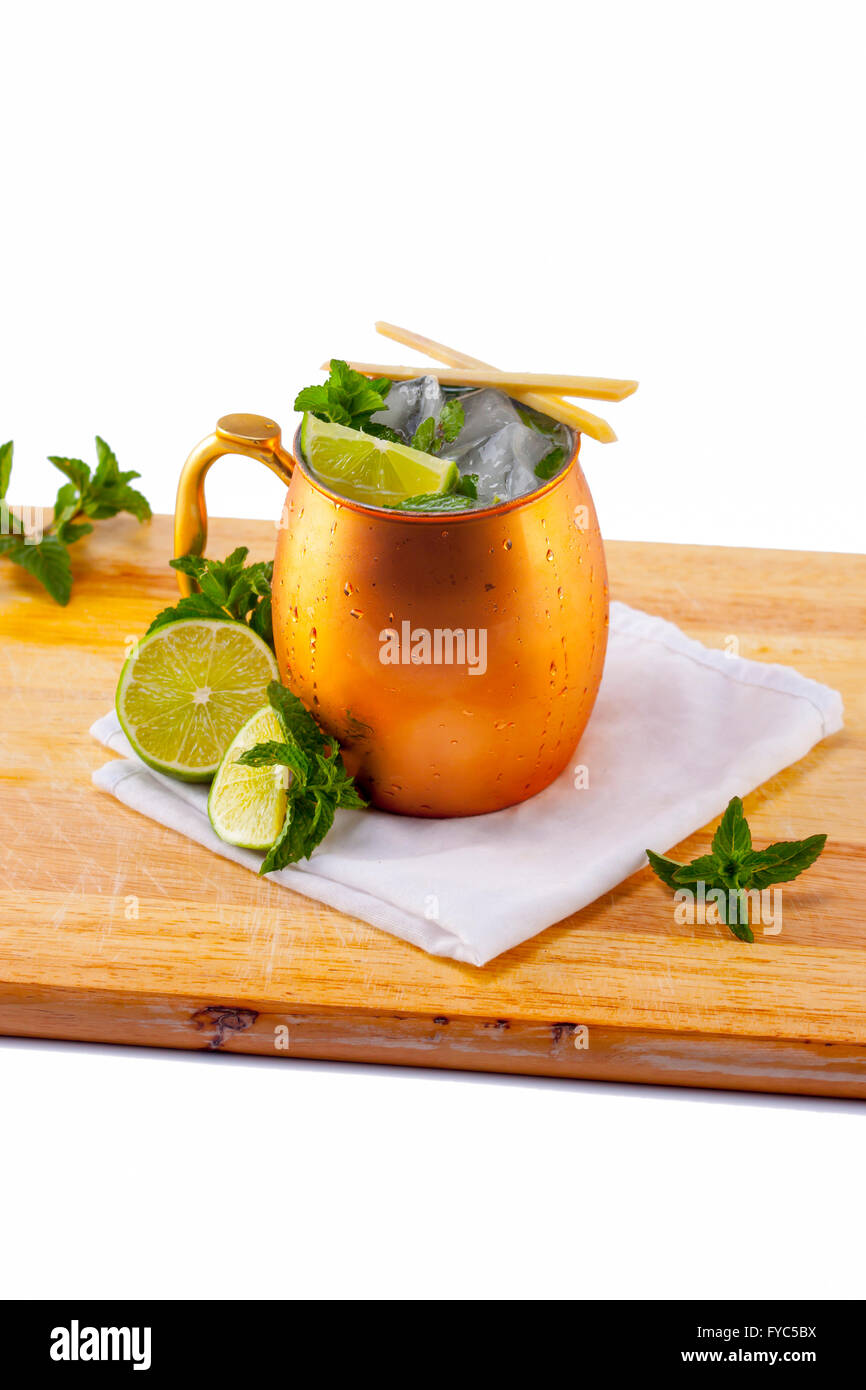 Ginger Beer Mule cocktail on cutting board with mint and lime garnishes Stock Photo