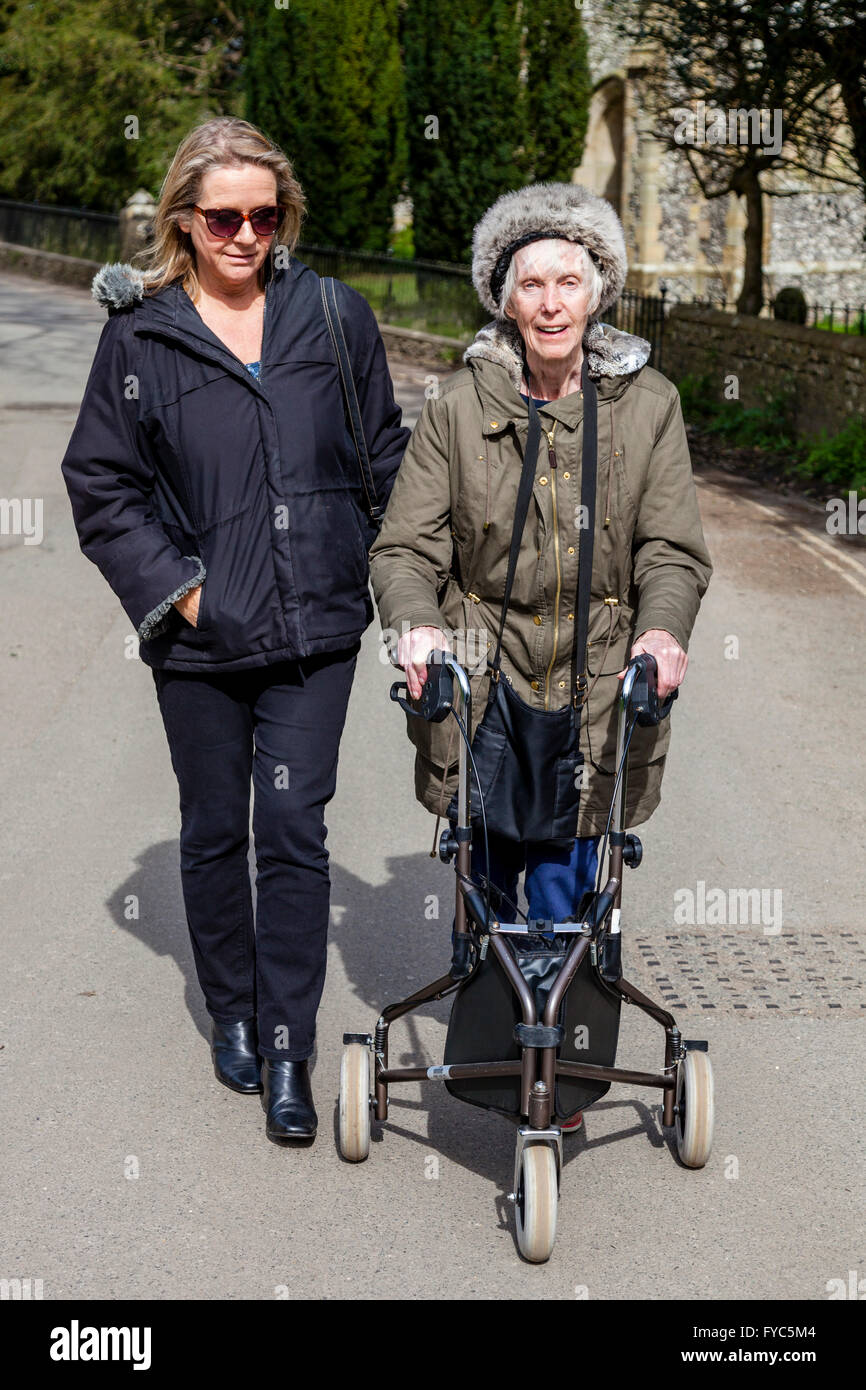 A Female Relative Walking With An Disabled Elderly Woman Using A Three Wheel Rollator, Sussex, UK Stock Photo