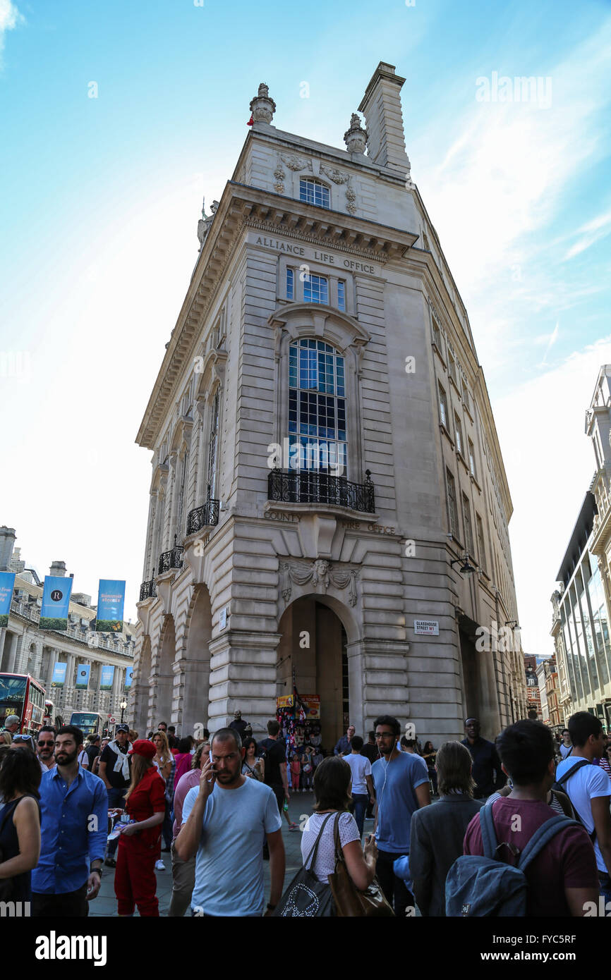 A crowd of people walks in front of the Alliance Life Office in Piccadilly Circus, London. Stock Photo