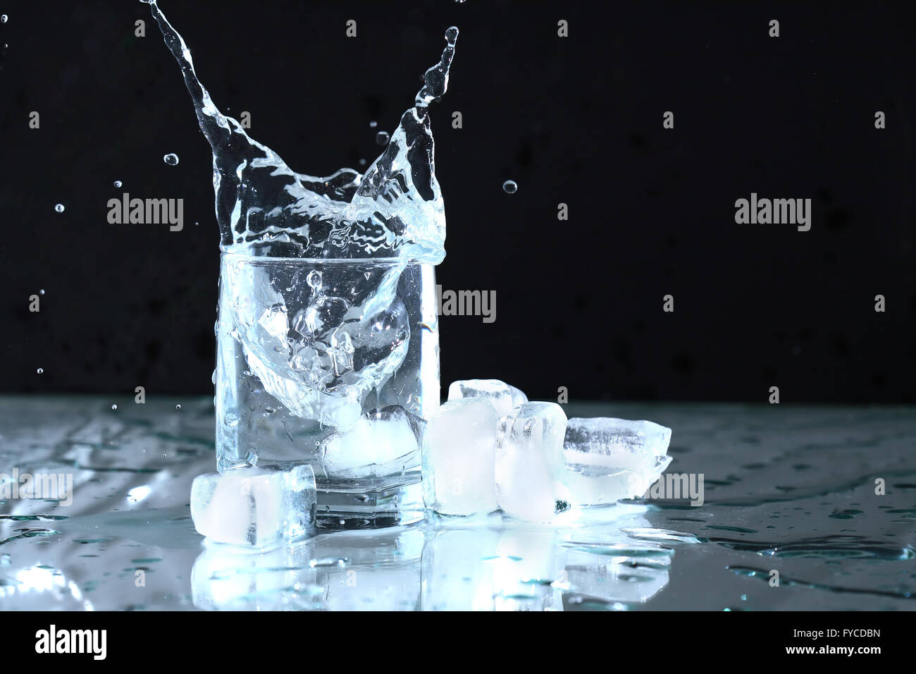 Glass with splashing water near ice cubes on dark background Stock ...