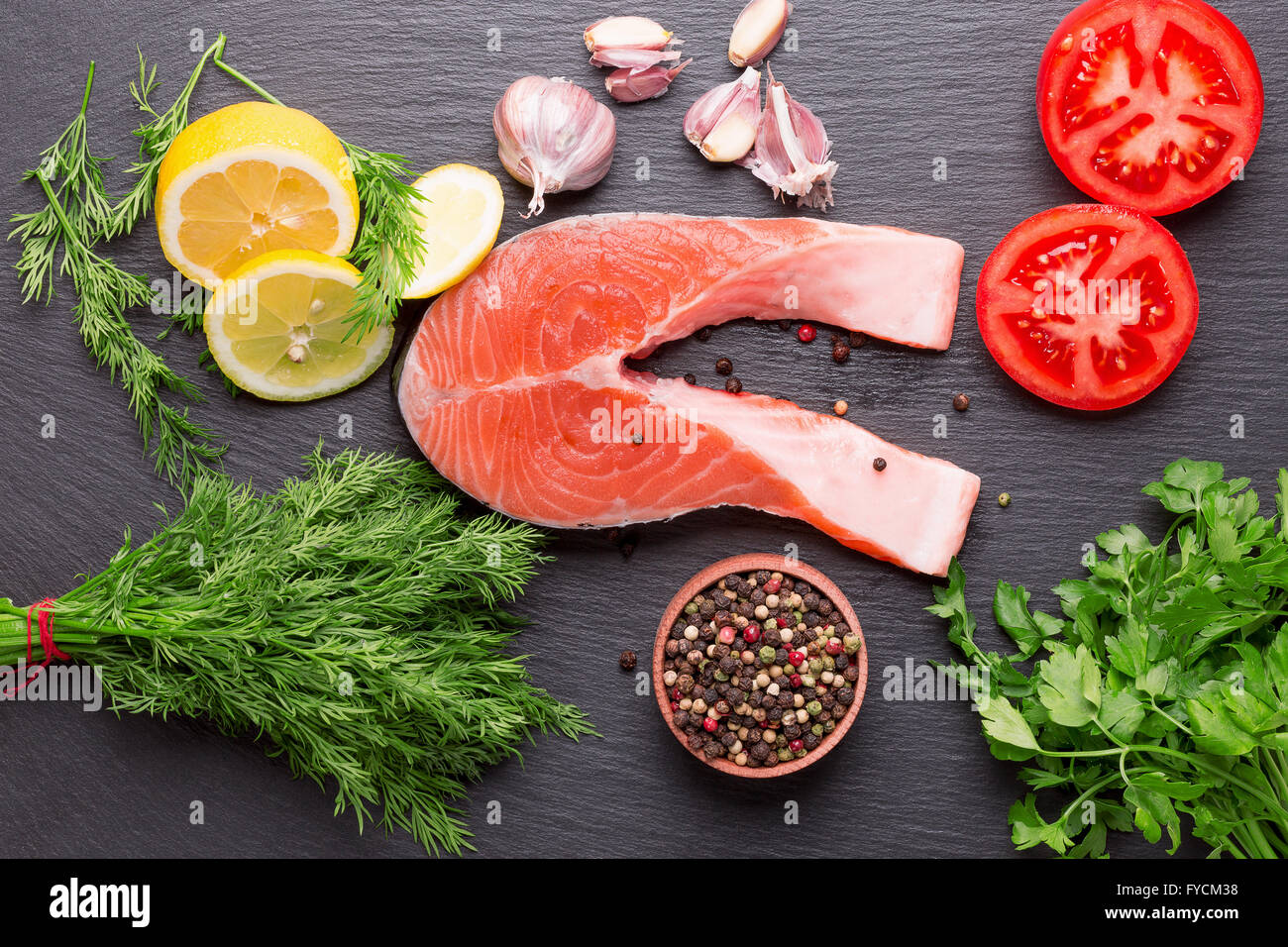 red fish steak with spices and vegetables on a slate table. Stock Photo