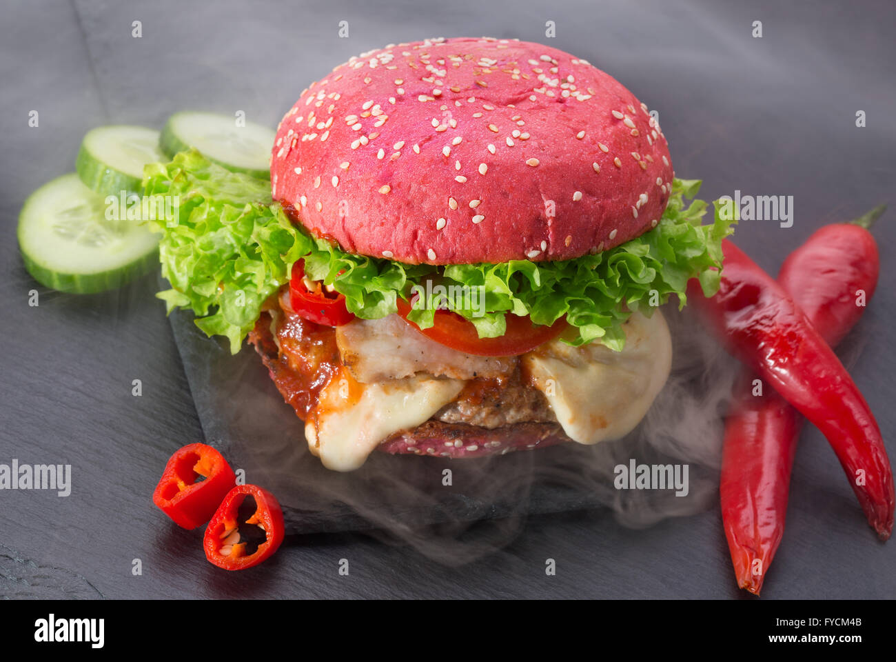 big red hamburger with smoke on a slate table. Stock Photo