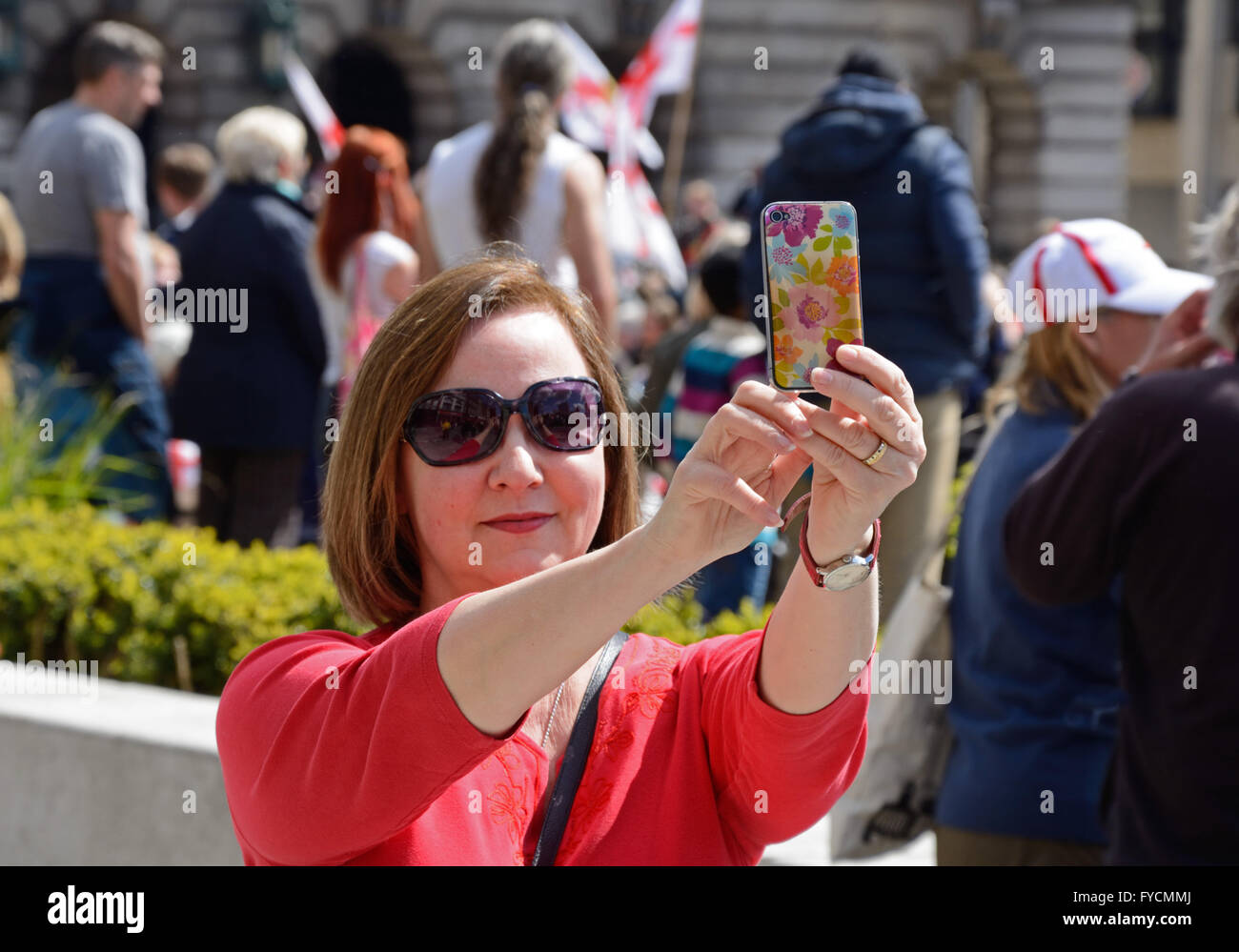 Lady taking selfie in a crowd. Stock Photo