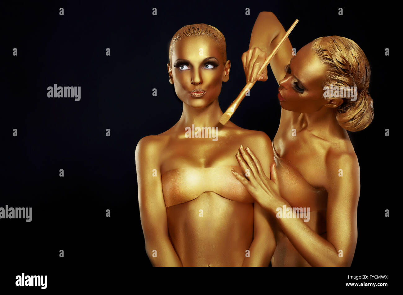 Two women painted in gold paint. Stock Photo