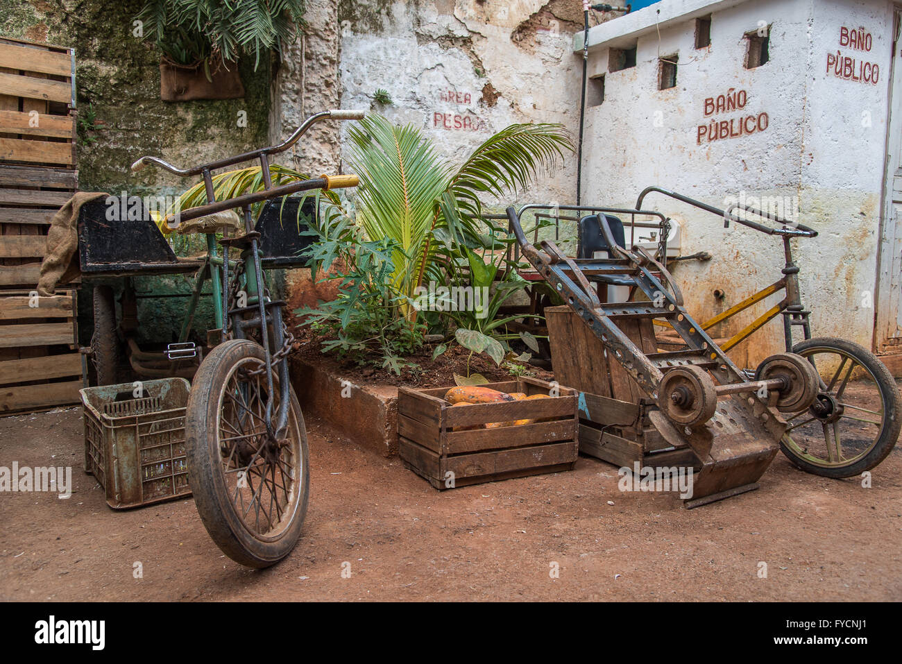 Bikes, crates and plants piled up outside a public toilet in a local market in Old Havana, Cuba. Bano Publico! Stock Photo