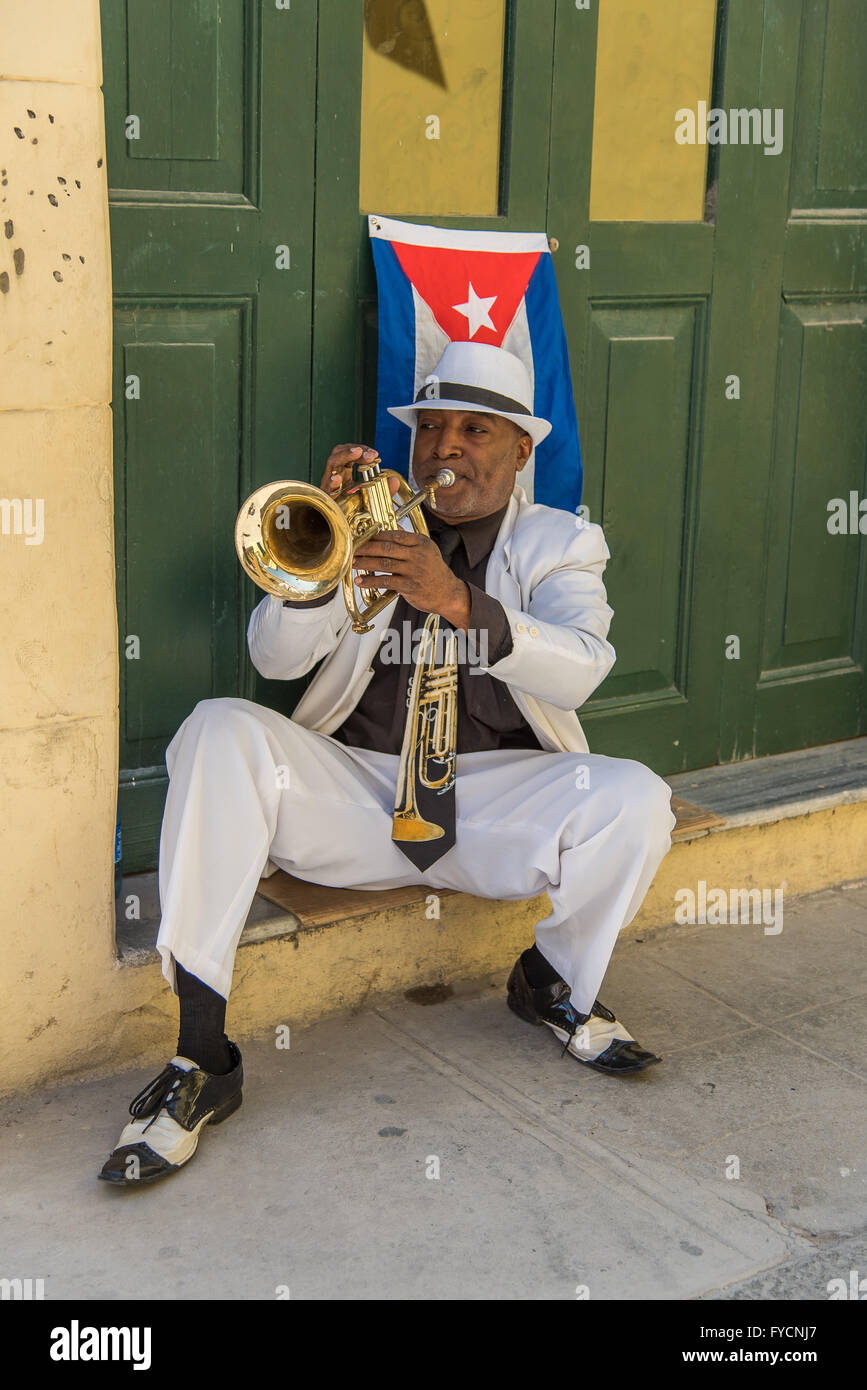 A Cuban musician plays his trumpet, wearing a trumpet neck tie. Sitting ...