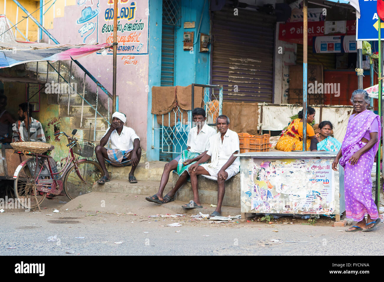 A group of Indian people sitting around passing time at the side of the ...