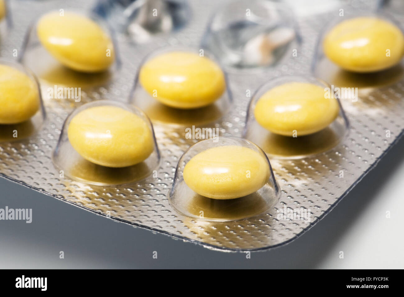 Yellow and round pills in a factory packing Stock Photo - Alamy