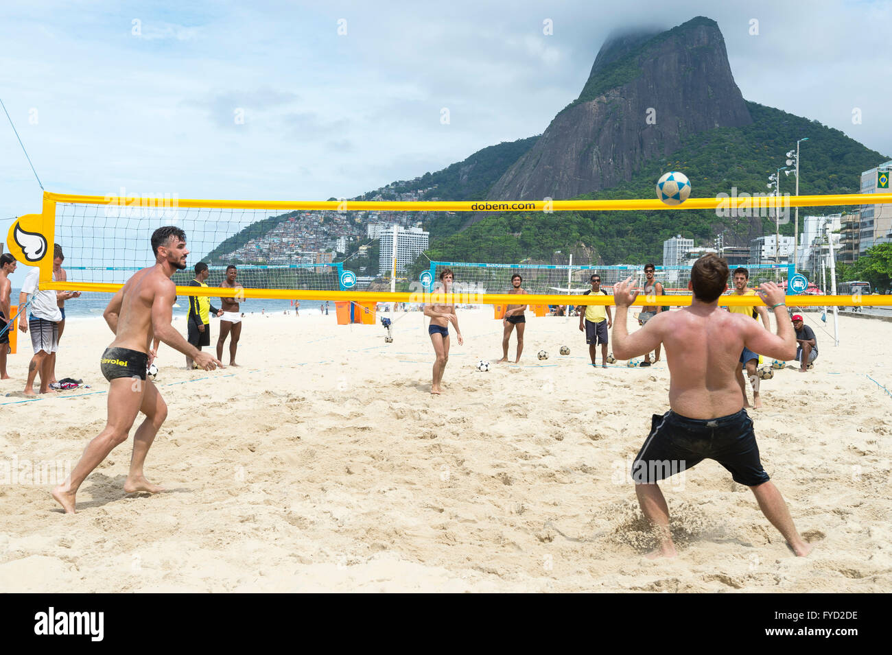 RIO DE JANEIRO - MARCH 17, 2016: Brazilian men play a game of futevôlei (footvolley, a sport combining football and volleyball. Stock Photo