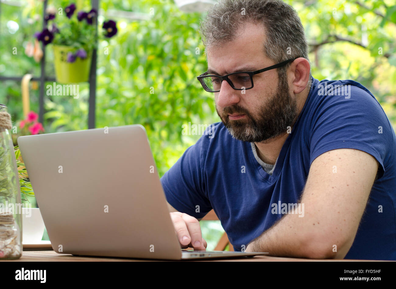Man sitting on a bench outside and working on laptop Stock Photo - Alamy