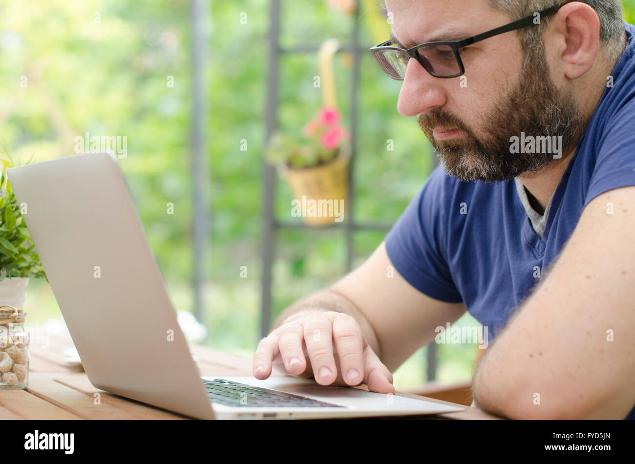 Man sitting on a bench outside and working on laptop Stock Photo - Alamy