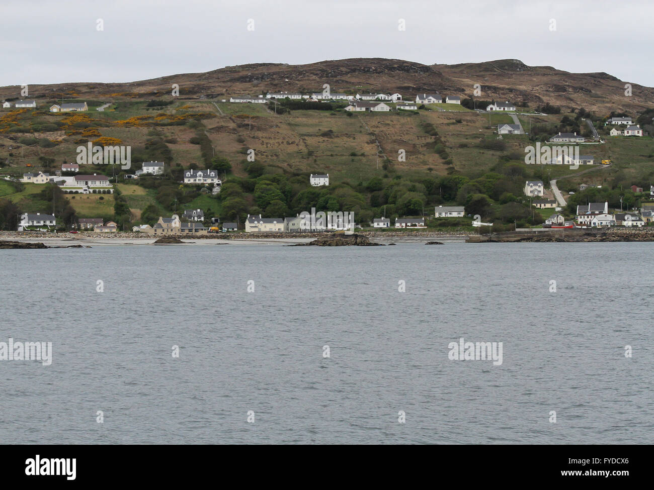 White houses in County Donegal on a hillside overlooking the harbour in the Gaeltacht village of Leabgarrow on the island of Arranmore, Ireland. Stock Photo