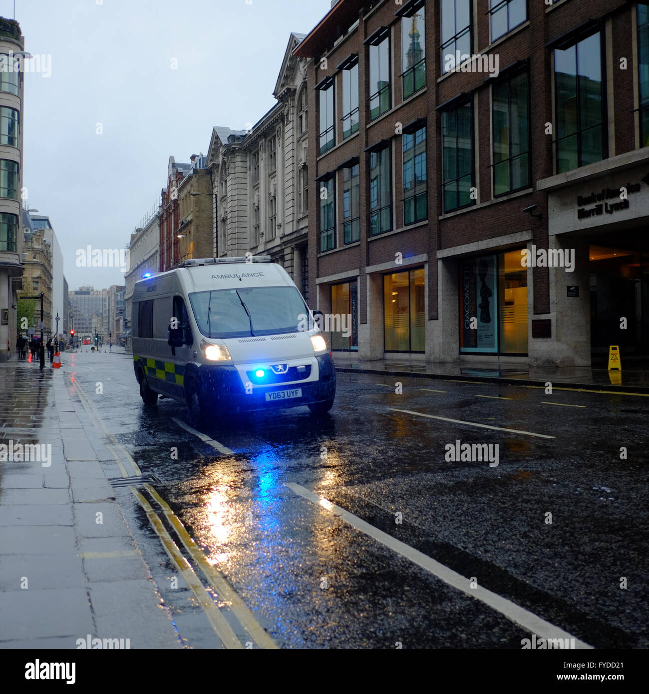 Ambulance responding to an emergency with blue lights flashing in London on a wet day Stock Photo