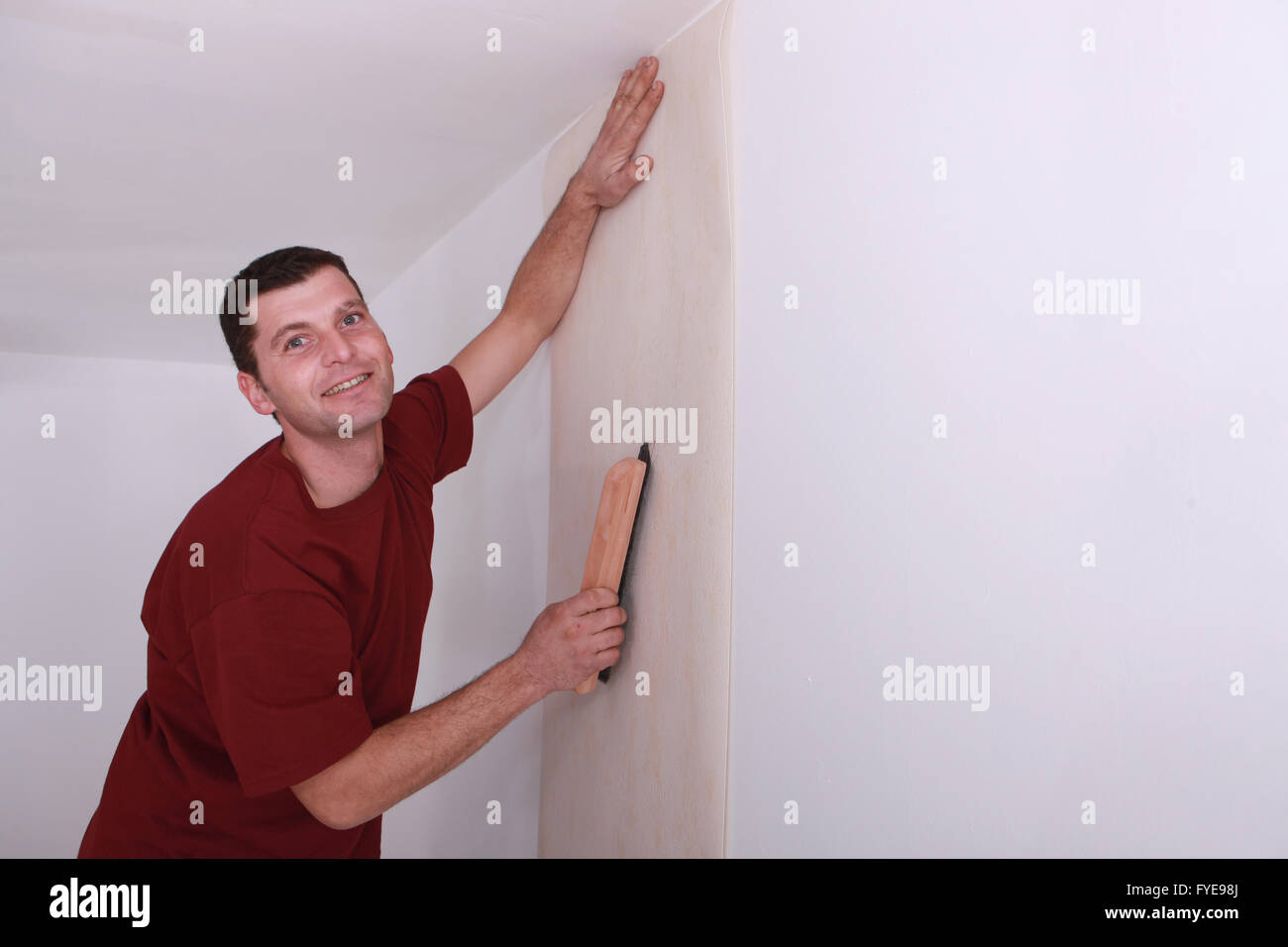 Decorator smoothing down wallpaper with a brush Stock Photo
