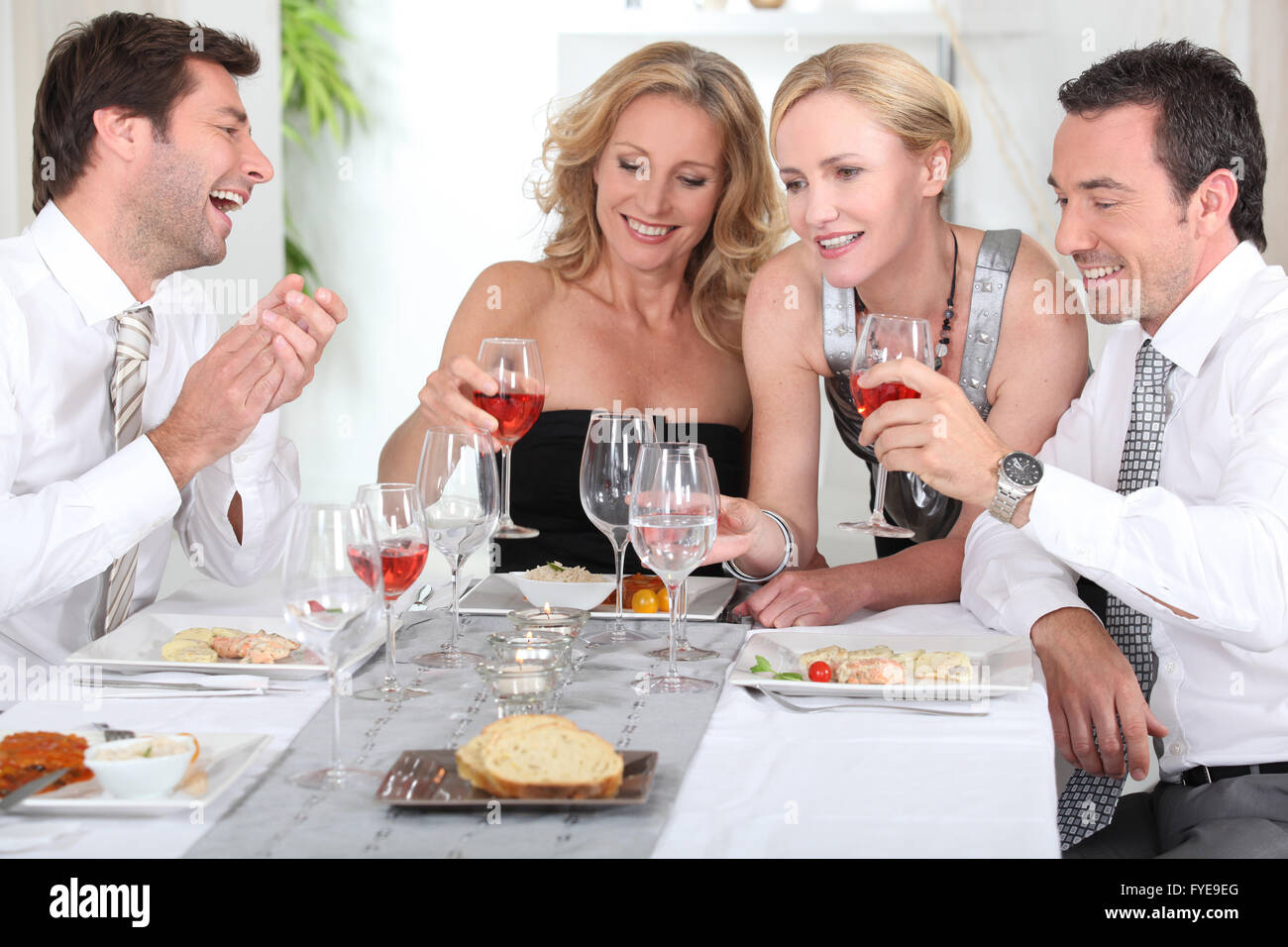 Four joyful people at the start of a posh dinner. Stock Photo