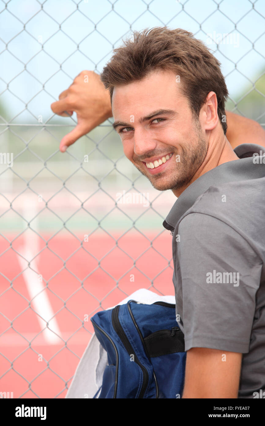 Smiling tennis player standing outside a hard court Stock Photo