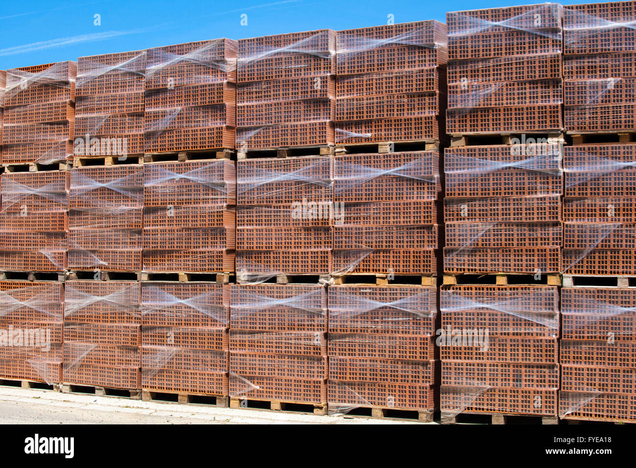 Many new bricks on stacked and foiled pallets, ready for transport and use. Stock Photo