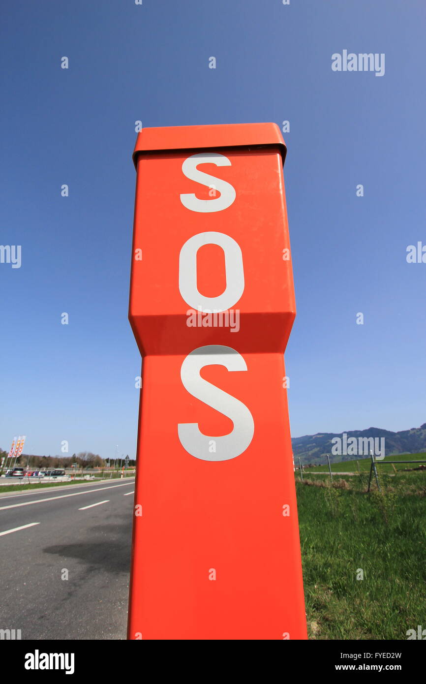 SOS orange sign next to a road by beautiful weathe Stock Photo